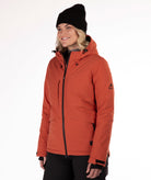 Woman wearing a rust colored winter jacket on a white background