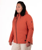 Woman wearing a rust colored winter jacket on a white background