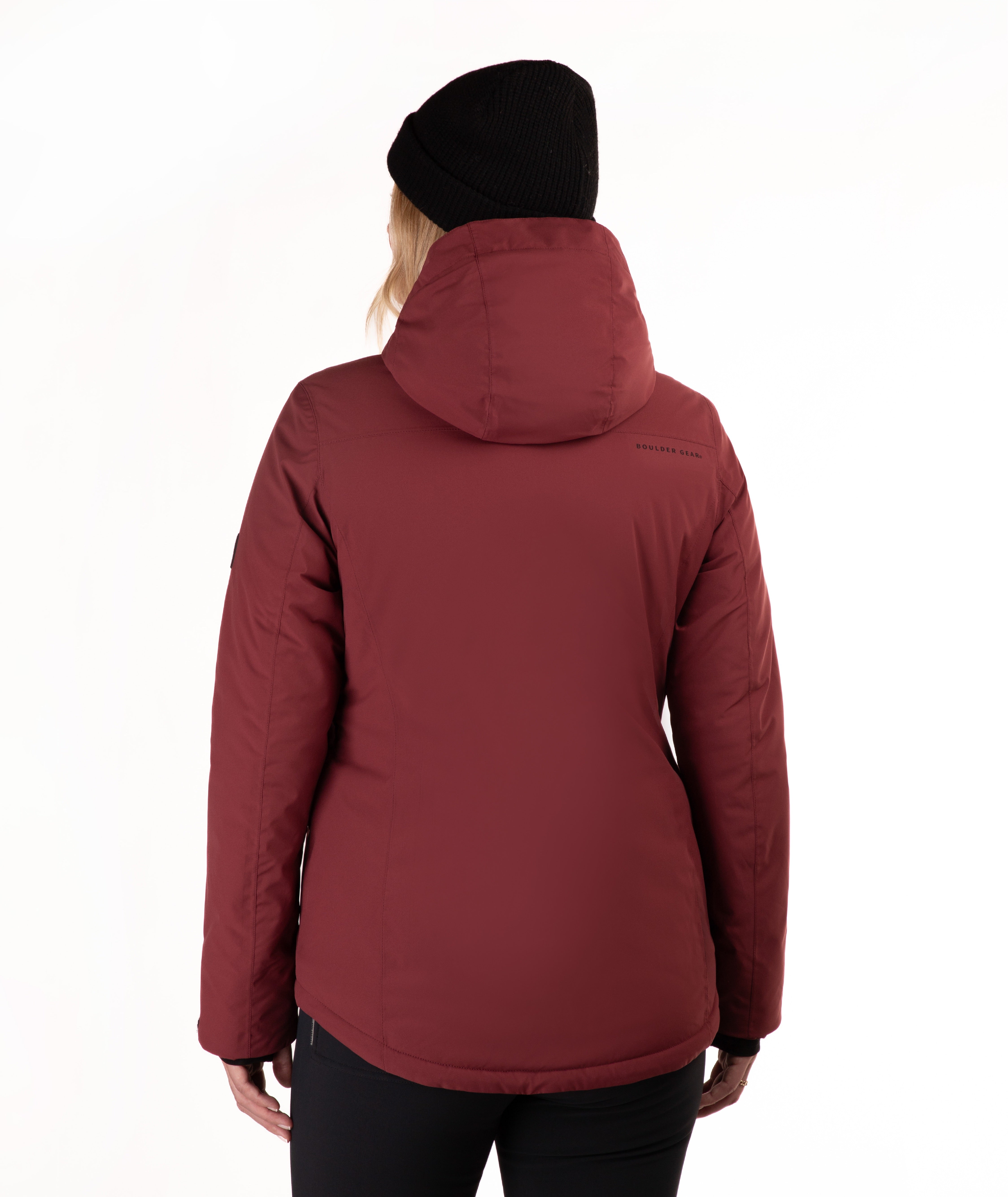 A woman viewed from the back wearing a dark red hooded puffer jacket, a black beanie, and black pants against a plain white background.