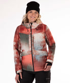 Person wearing an abstract printed jacket in primarily rust, gray and beige with a white background