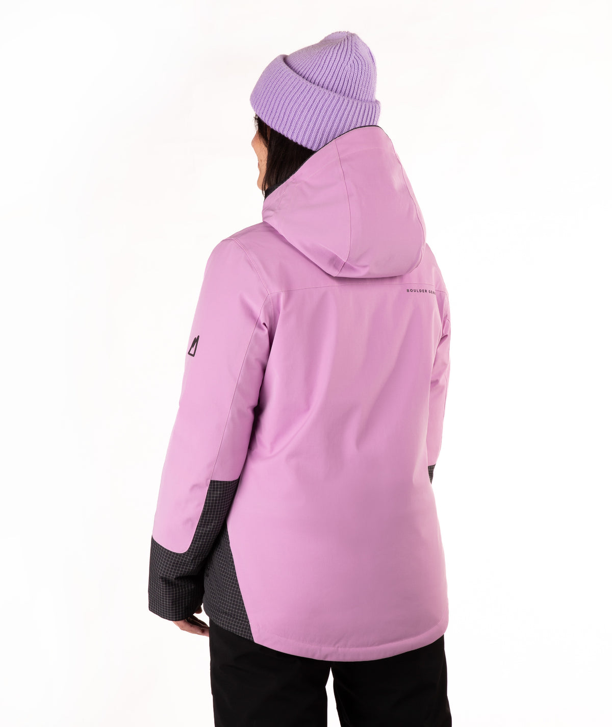 A person shown from the back wearing a light purple ski jacket with black accents on the lower sleeves and sides, paired with a light purple ribbed knit beanie and black pants, against a plain white background.