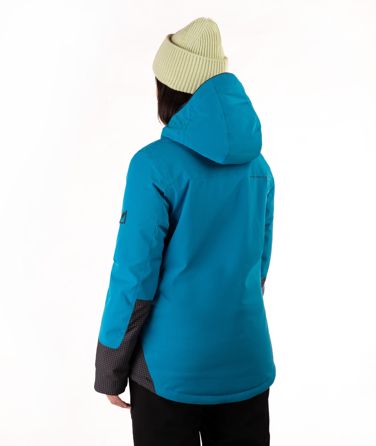 A person shown from the back wearing a bright turquoise hooded jacket with black accents, a green ribbed beanie, and black pants against a plain white background.