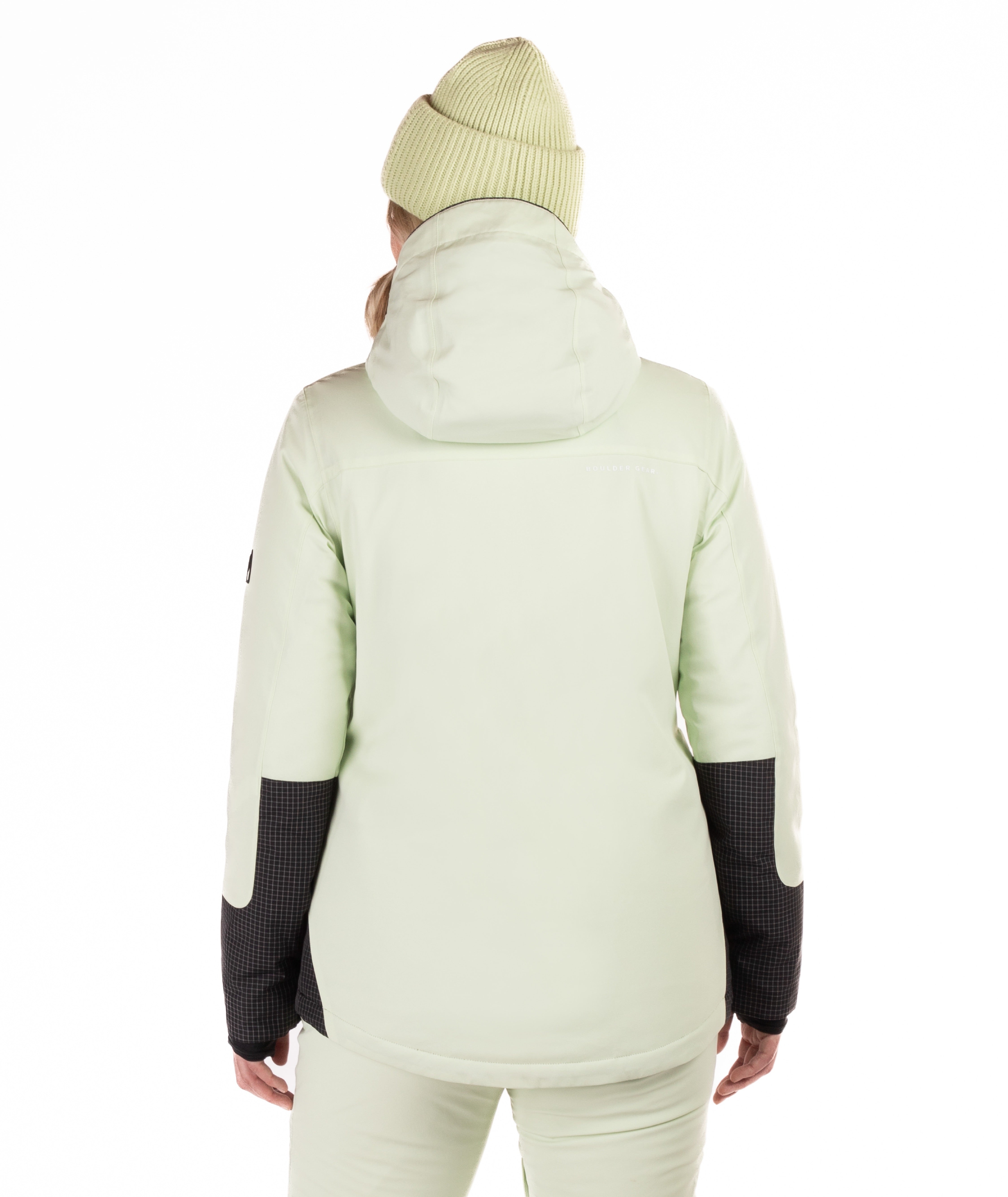 Woman wearing a two-tone light green and black checked jacket with a white background highlighting the back of the jacket and hood and sleeve details