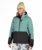 Woman wearing a teal and black jacket with a white background