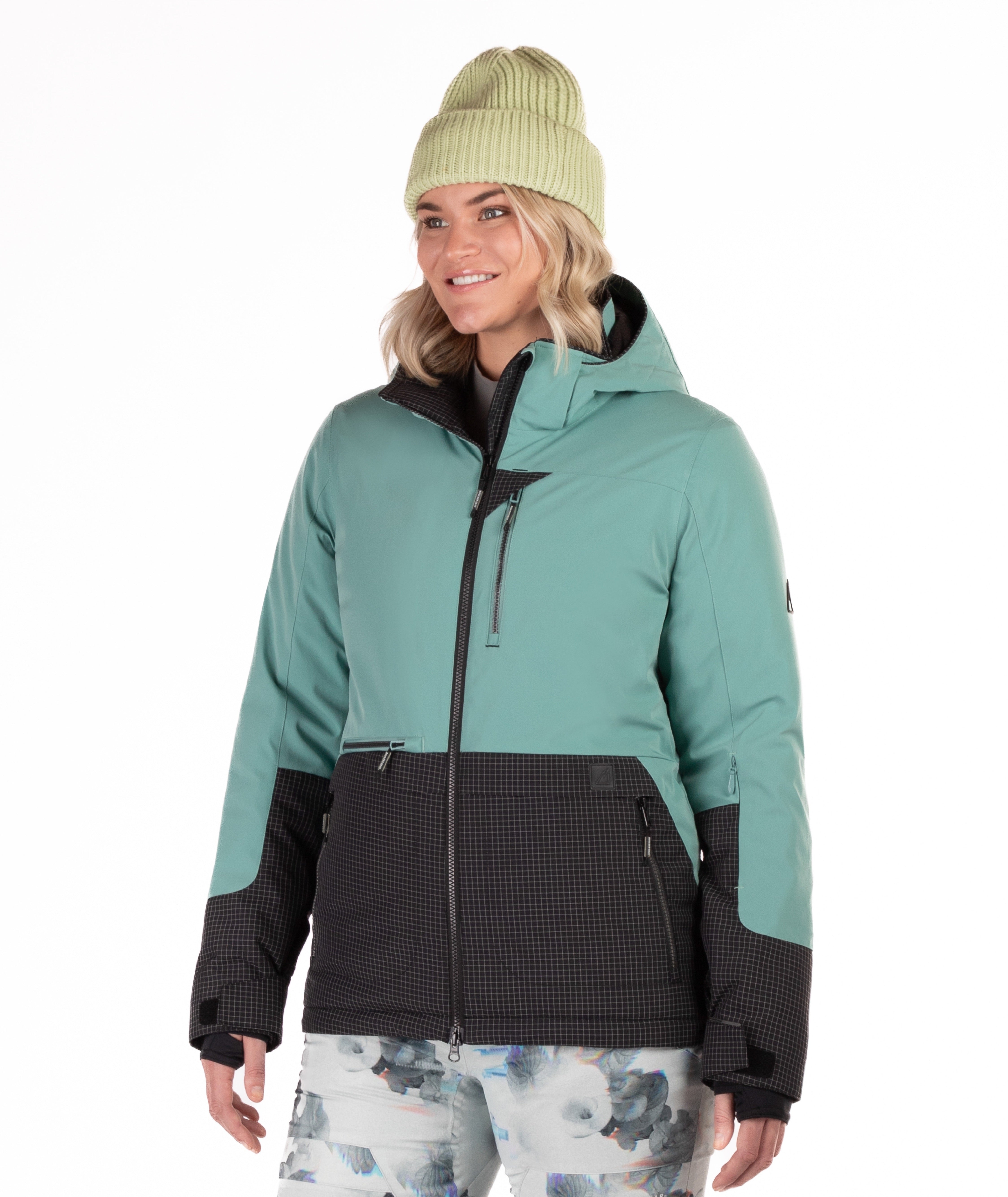 Woman wearing a teal and black jacket with a white background