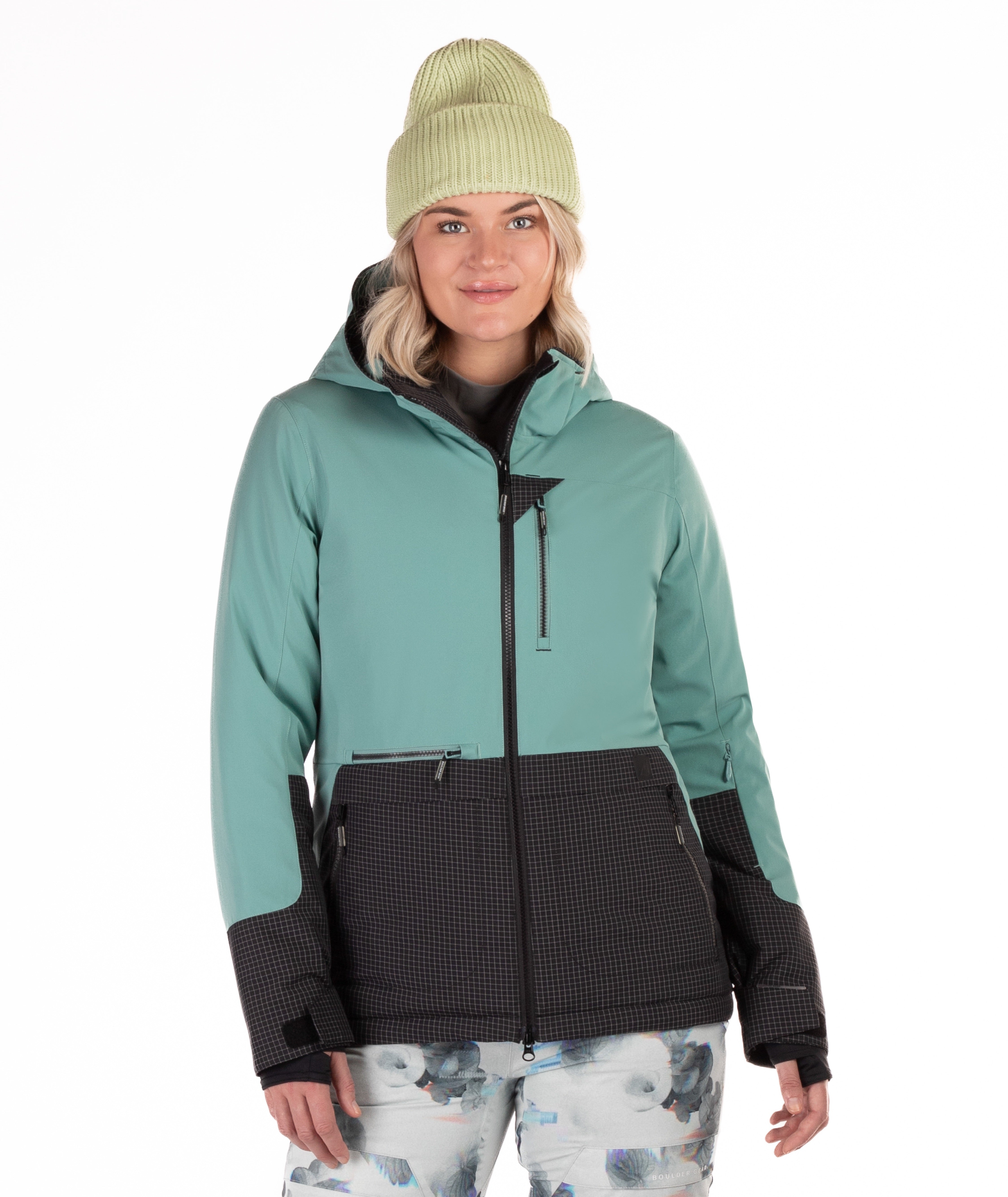 Woman wearing a teal and black jacket with a white background