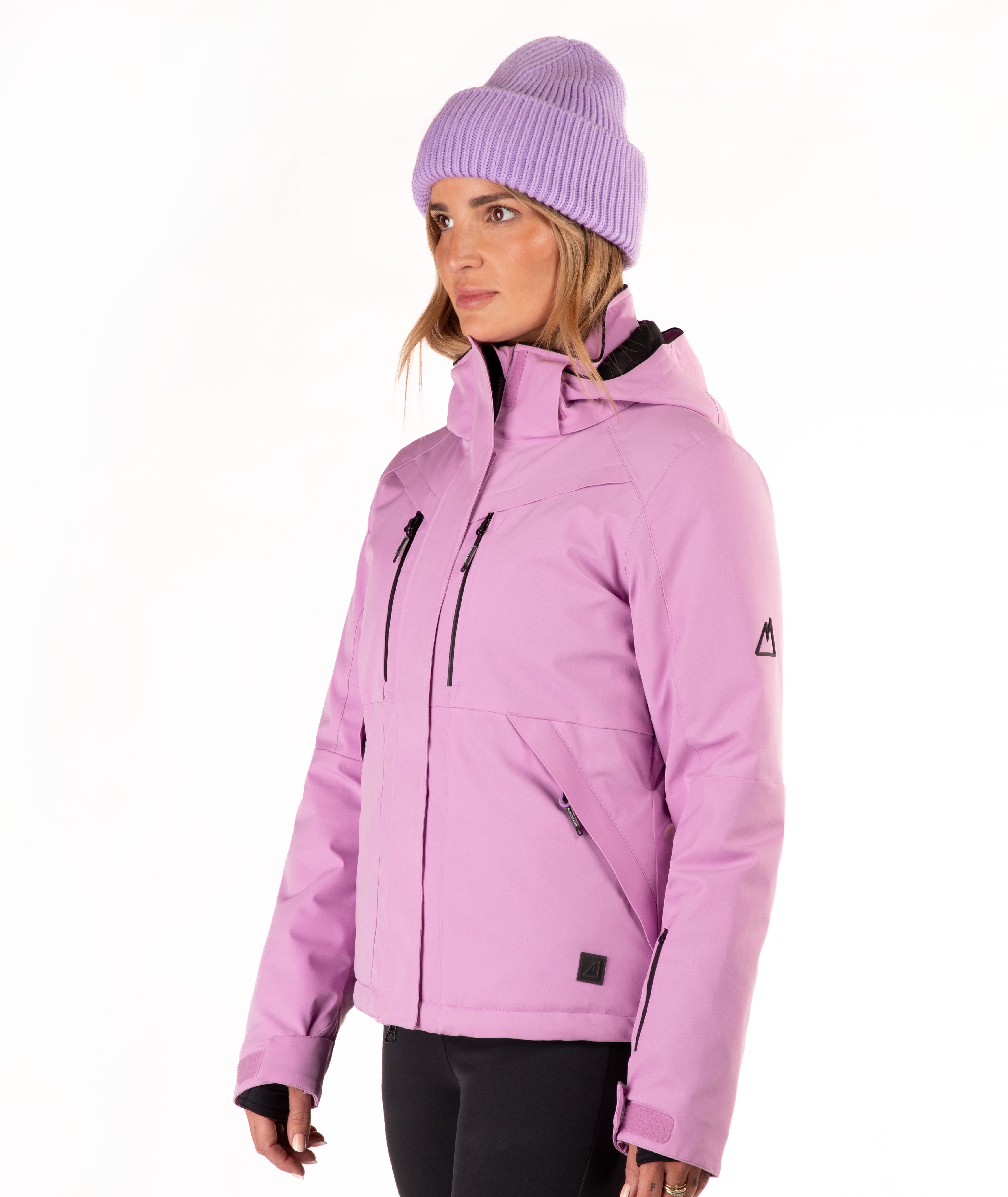 A woman wearing a light purple/lavender ski jacket and a matching knit beanie against a plain white studio background.
