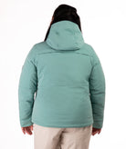 Woman wearing a teal snow jacket with black chest zippers on a white background highlighting back of jacket and hood