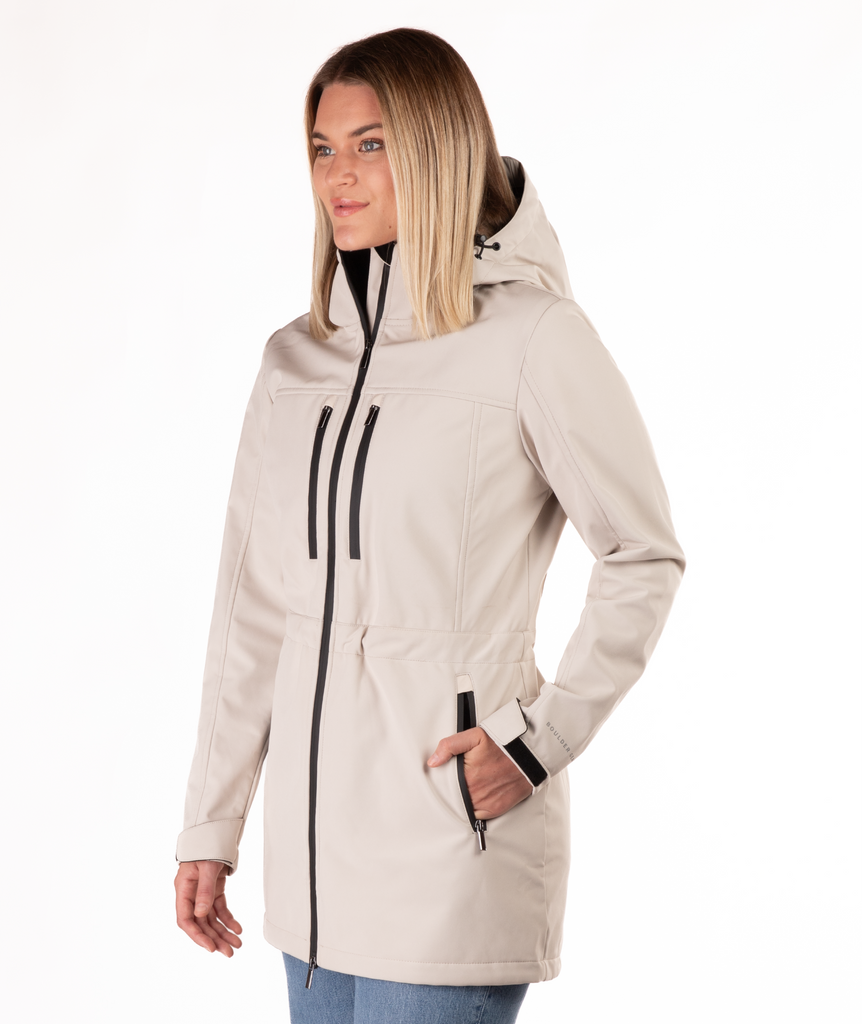 Woman wearing a beige winter coat with black zippers on a white background
