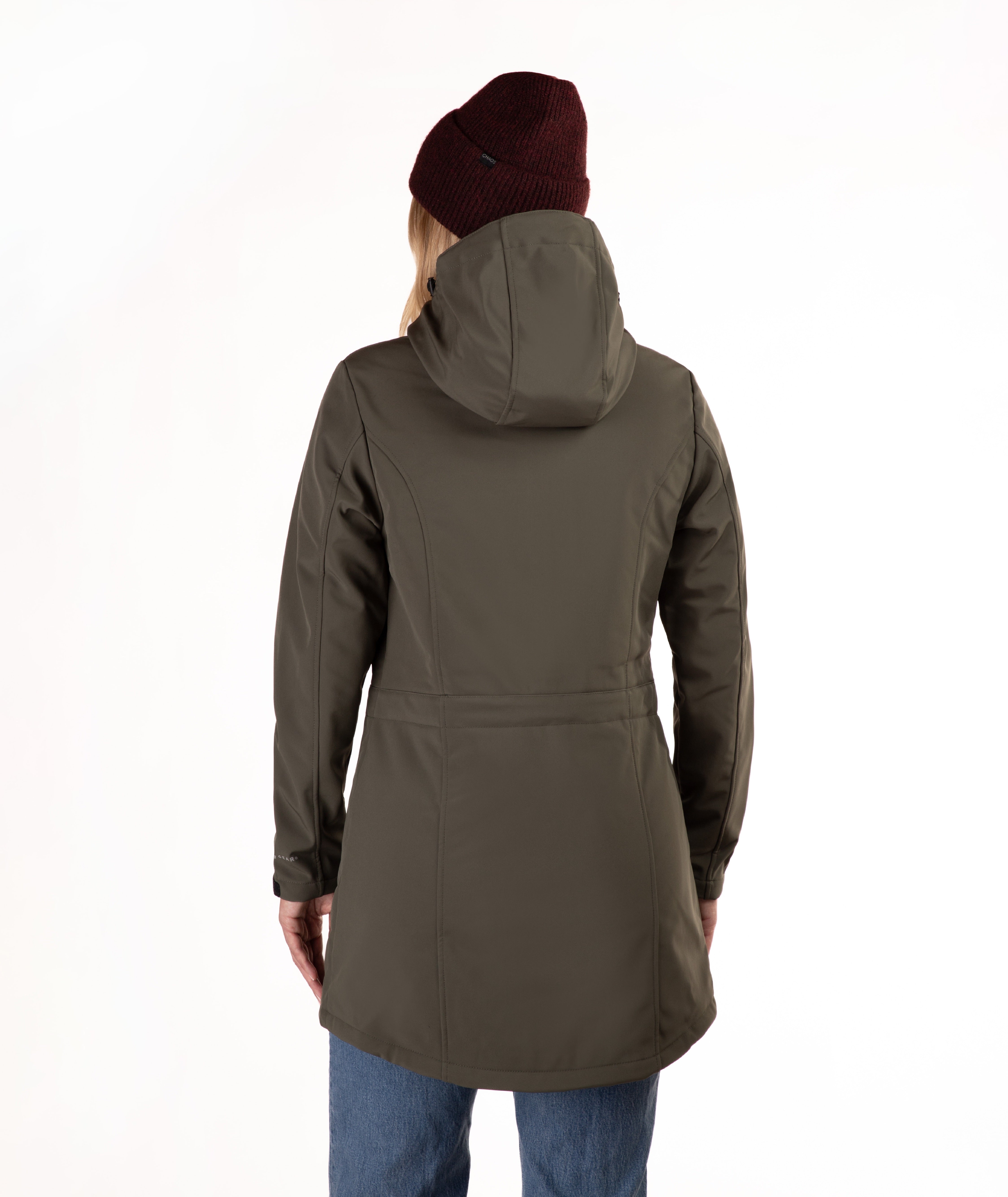 A woman viewed from the back wearing an olive green hooded jacket, a burgundy knit beanie, and blue jeans against a plain white background.