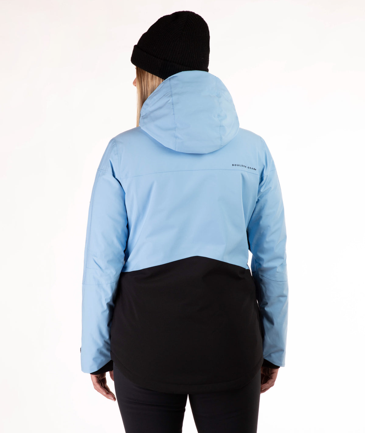 A woman wearing a light blue and black color-blocked ski jacket, a black beanie, and black pants, photographed against a plain white studio background.