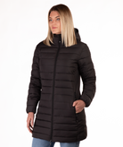Woman wearing a black mid thigh length puffer coat on a white background
