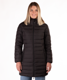 Woman wearing a black mid thigh length puffer coat on a white background
