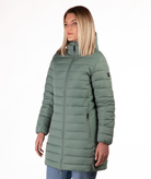 Woman wearing a green mid thigh length puffer coat on a white background