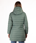 Woman wearing a green mid thigh length puffer coat on a white background