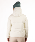 Woman wearing a black quilted winter jacket on a white background showing the back of the jacket and hood