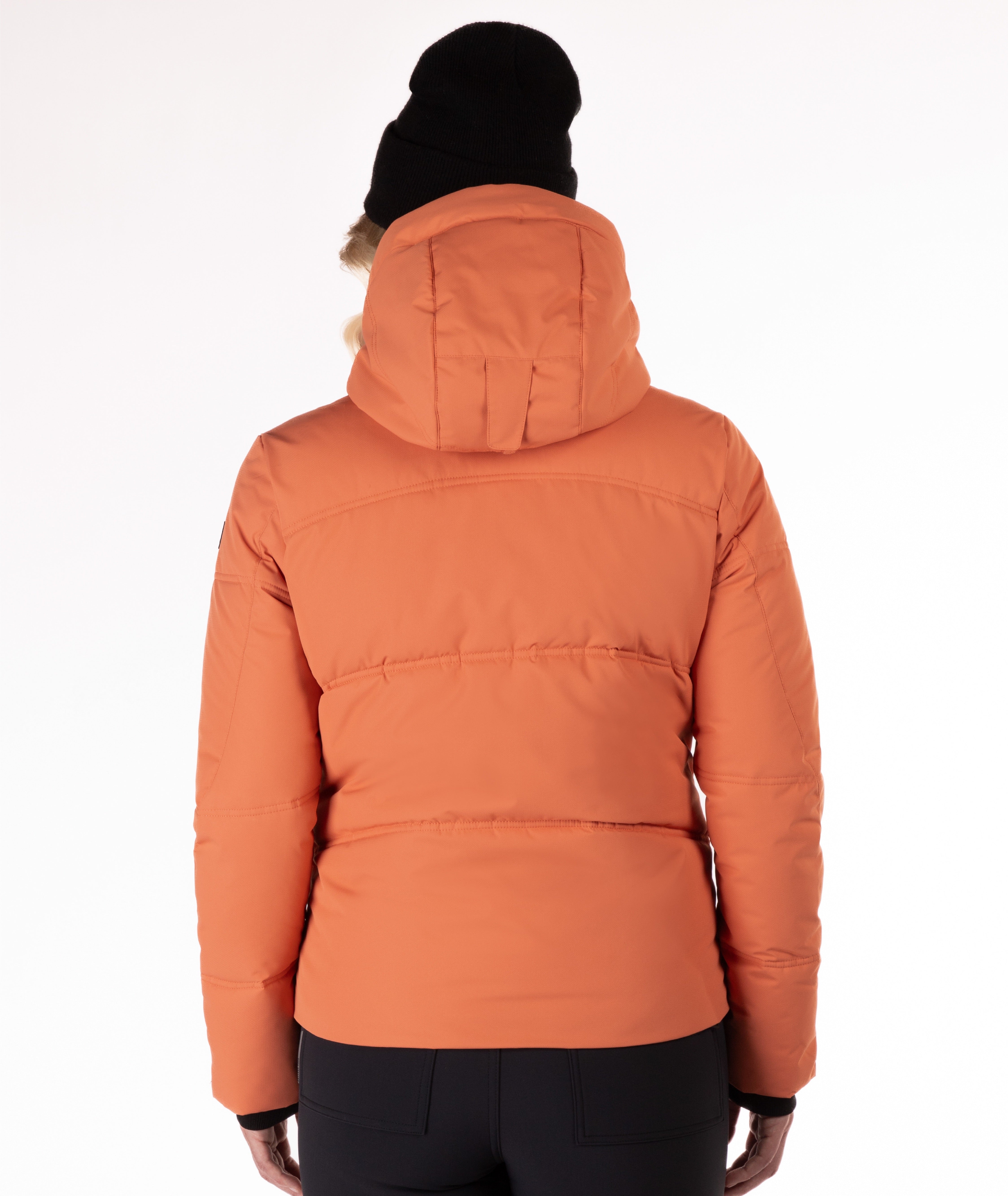 Woman wearing a coral quilted winter jacket on a white background