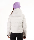 A person shown from the back wearing a light off-white puffer jacket, a lavender ribbed knit beanie, and black pants against a plain white studio background.