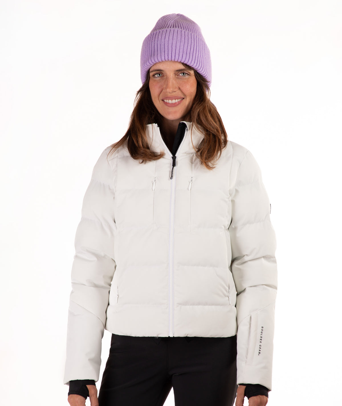 A woman wearing a off white puffer jacket, black pants, and a light purple knit beanie, standing against a plain white background.