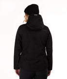 A woman viewed from the back wearing a black hooded jacket and a black beanie, photographed against a clean white studio background.