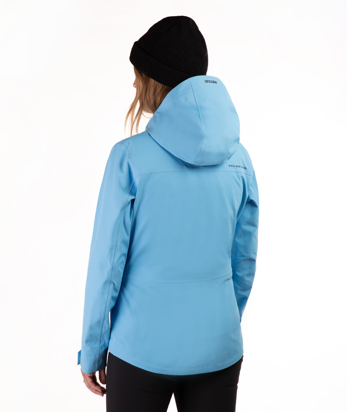 A woman wearing a light blue hooded ski jacket and a black beanie, shown from the back against a plain white studio background.