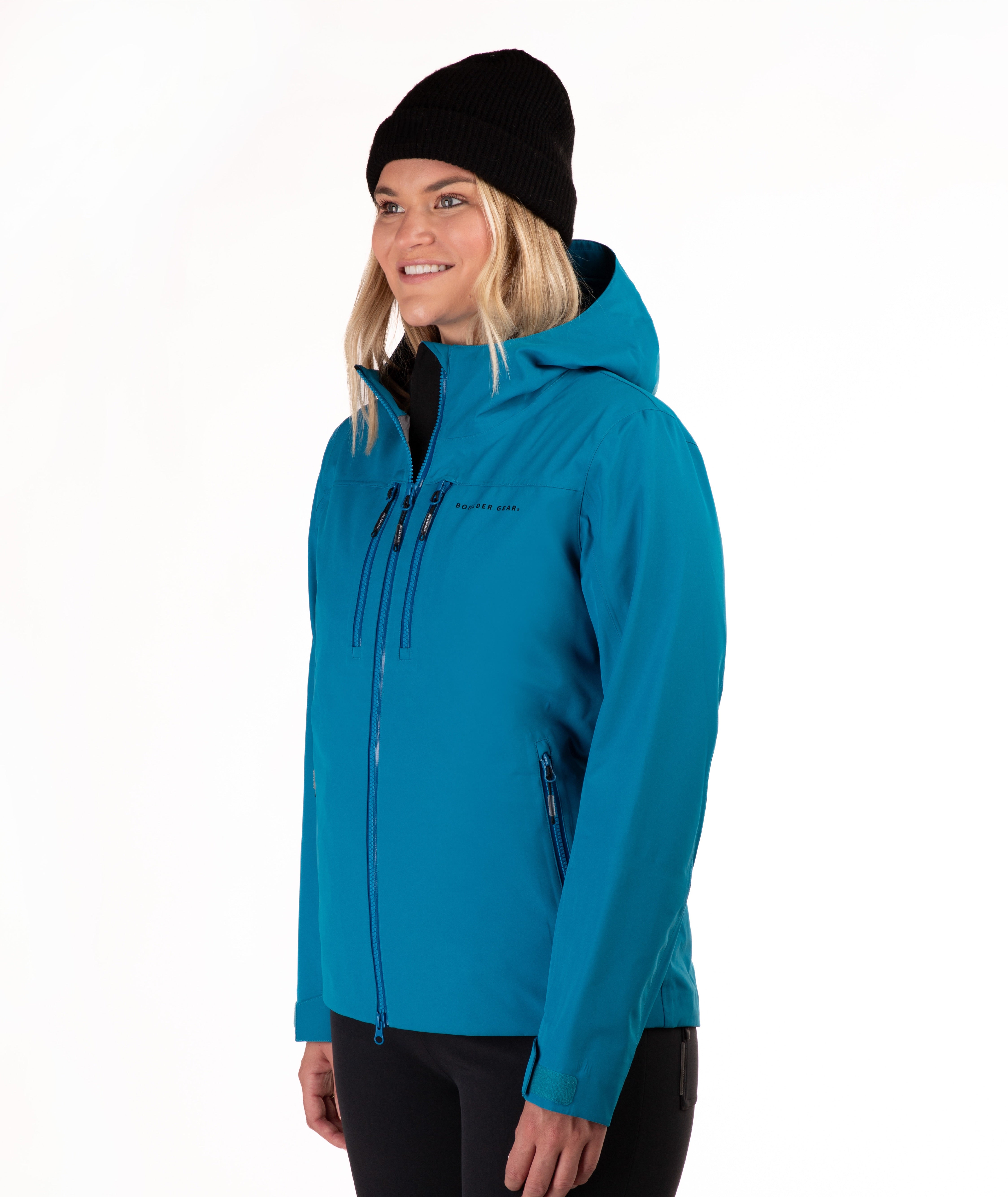 A woman wearing a bright turquoise hooded jacket, black beanie, and black pants, photographed against a clean white studio background.