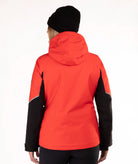 A woman viewed from behind wearing a bright red hooded jacket with black sleeves and a black beanie, against a plain white studio background.