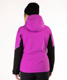 A woman viewed from the back wearing a bright pink hooded jacket with black sleeves and a black beanie, against a plain white studio background.
