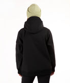 A person shown from the back wearing a black hooded jacket and a light green knit beanie against a plain white studio background.