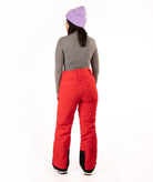 A person shown from the back wearing bright red snow pants, a gray long-sleeve top, and a light purple knit beanie against a plain white studio background.