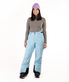 Person wearing light blue snow pants and a gray top with a white background
