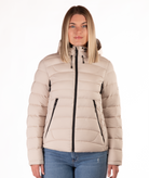 Woman wearing a beige puffer jacket on a white background