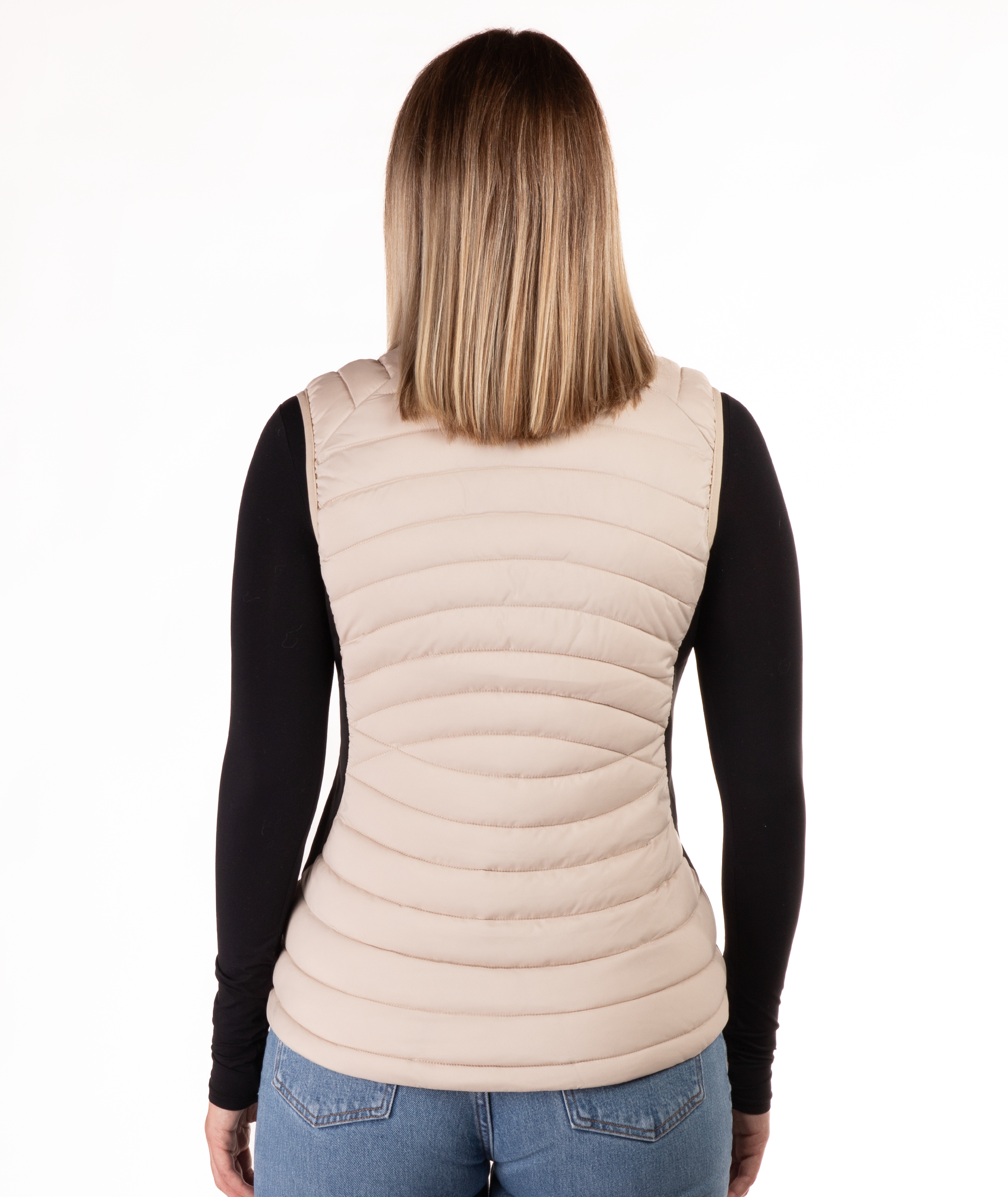 back of a woman wearing a beige puffer vest over a black long-sleeve shirt on a white background