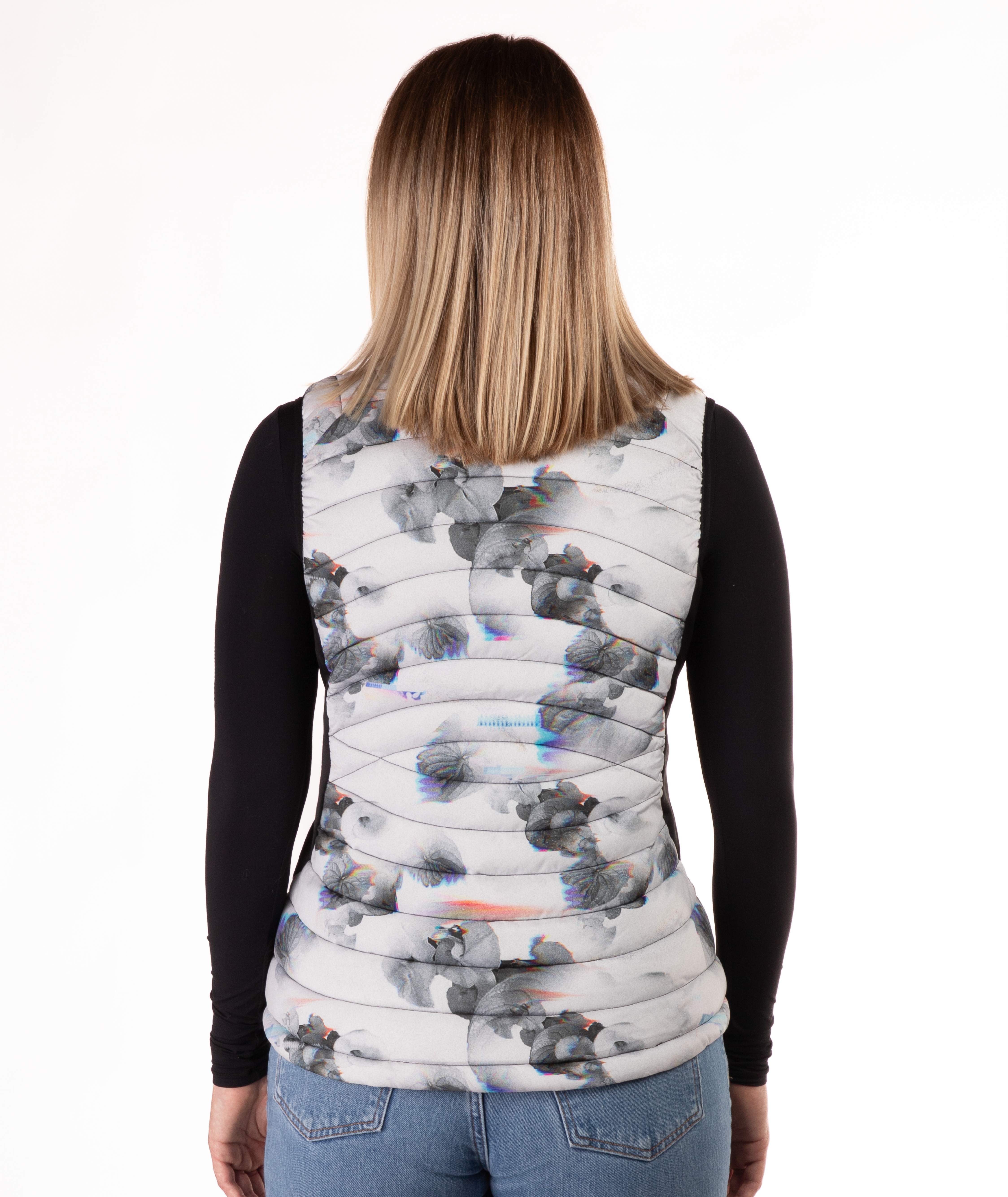 back of a woman wearing a flower patterned puffer vest over a black long-sleeve shirt on a white background