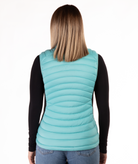 back of woman wearing a turquoise puffer vest over a black long-sleeve shirt on a white background