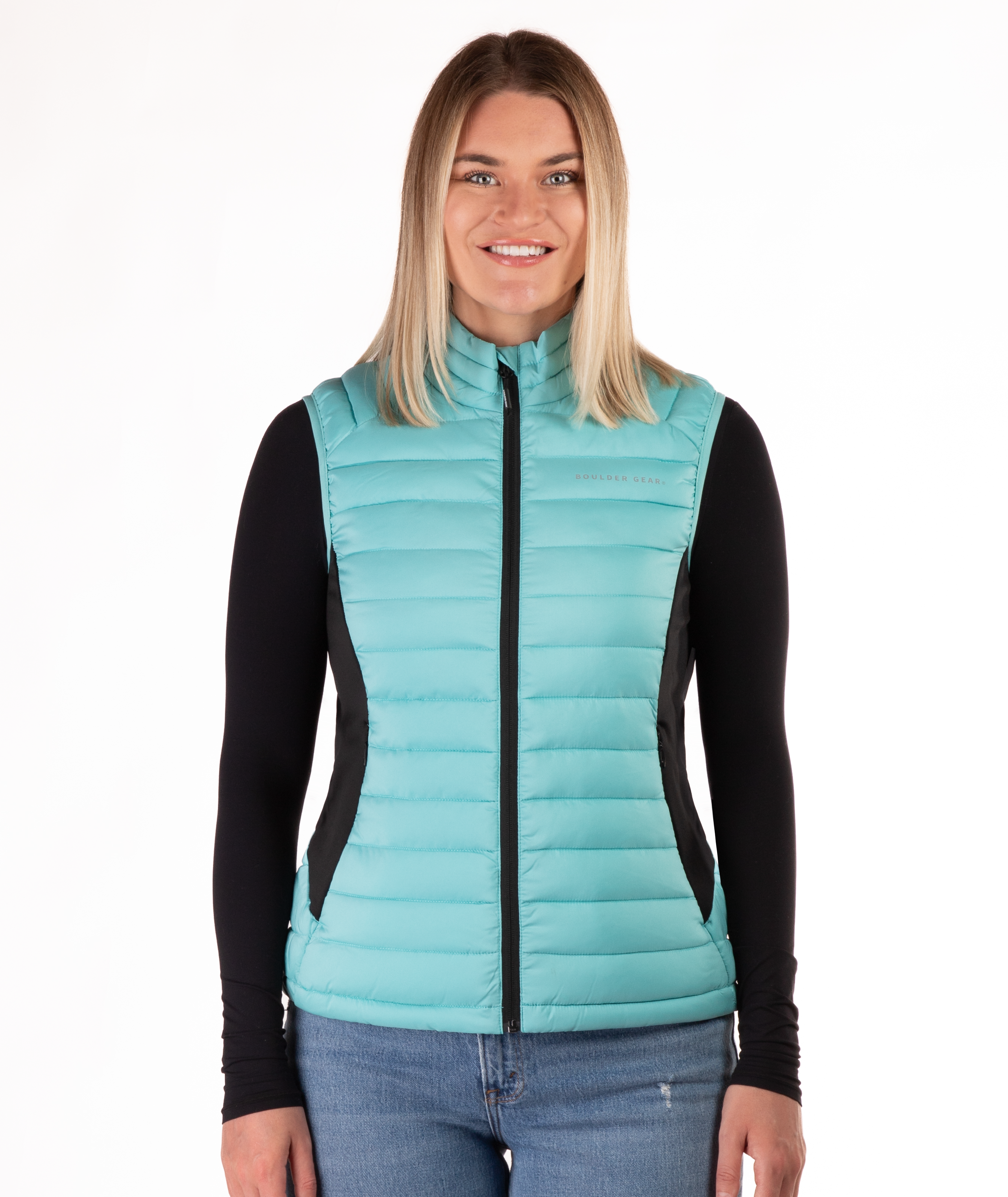 Woman wearing a turquoise puffer vest over a black long-sleeve shirt on a white background