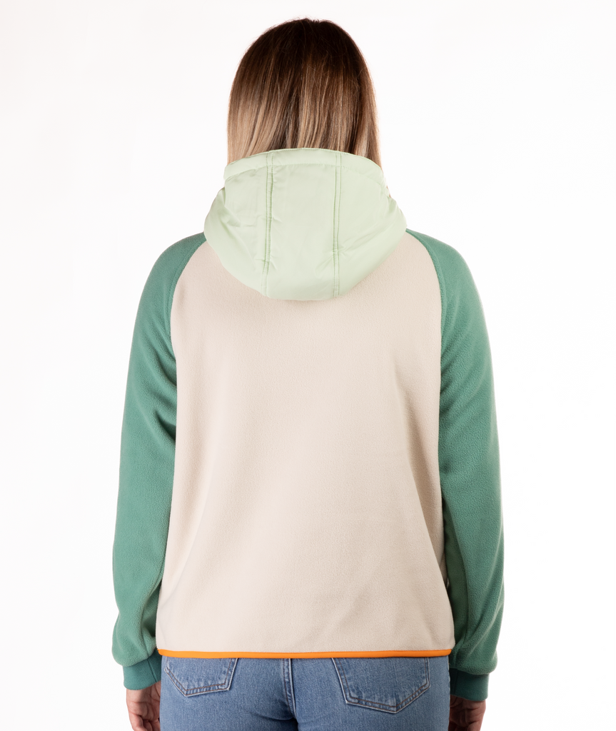 back of woman wearing a green and beige fleece pullover with hood and orange detailing on a white background