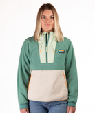 Woman wearing a green and beige fleece pullover with a visible brand logo and orange detailing on a white background
