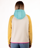 back of woman wearing a yellow, blue and beige fleece pullover with hood and pink detailing on a white background