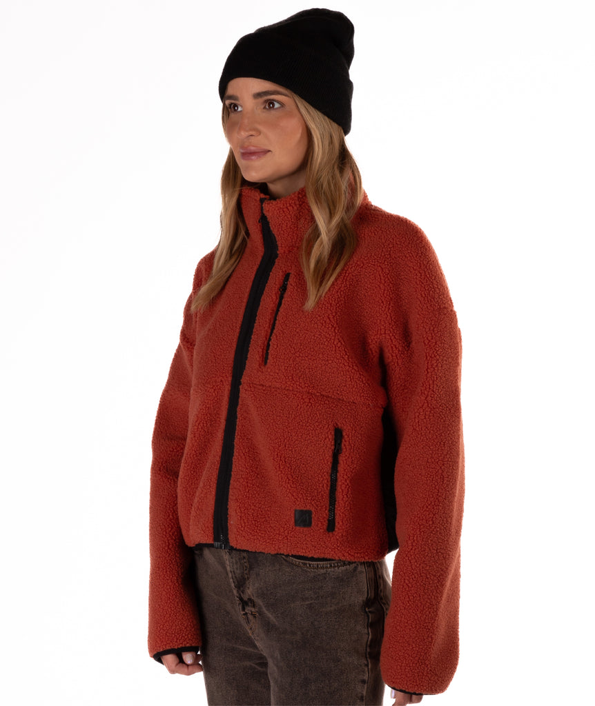 Person wearing a red fleece jacket with black zipper details on a white background