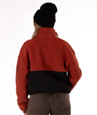 back of Person wearing a red fleece jacket with black zipper on a white background