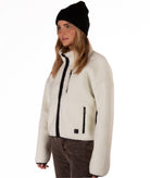 Person wearing a cream fleece jacket with black zipper on a white background