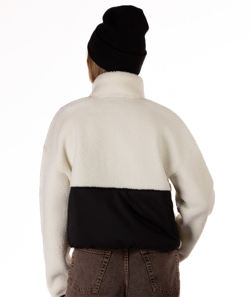 Person wearing a white fleece jacket with a black panel on a white background shown from behind