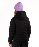 A person shown from the back wearing a black quilted puffer jacket and a light purple ribbed knit beanie against a plain white background.