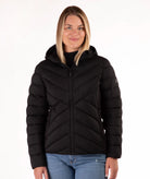 A woman wearing a black hooded puffer jacket with a full-zip front, shown against a plain white studio background.