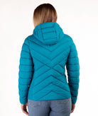 A woman viewed from the back wearing a teal quilted puffer jacket with a hood and chevron stitching, paired with blue jeans, against a plain white background.