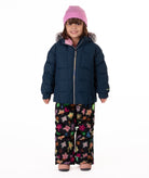 Child wearing a navy blue quilted puffy winter coat on a white background