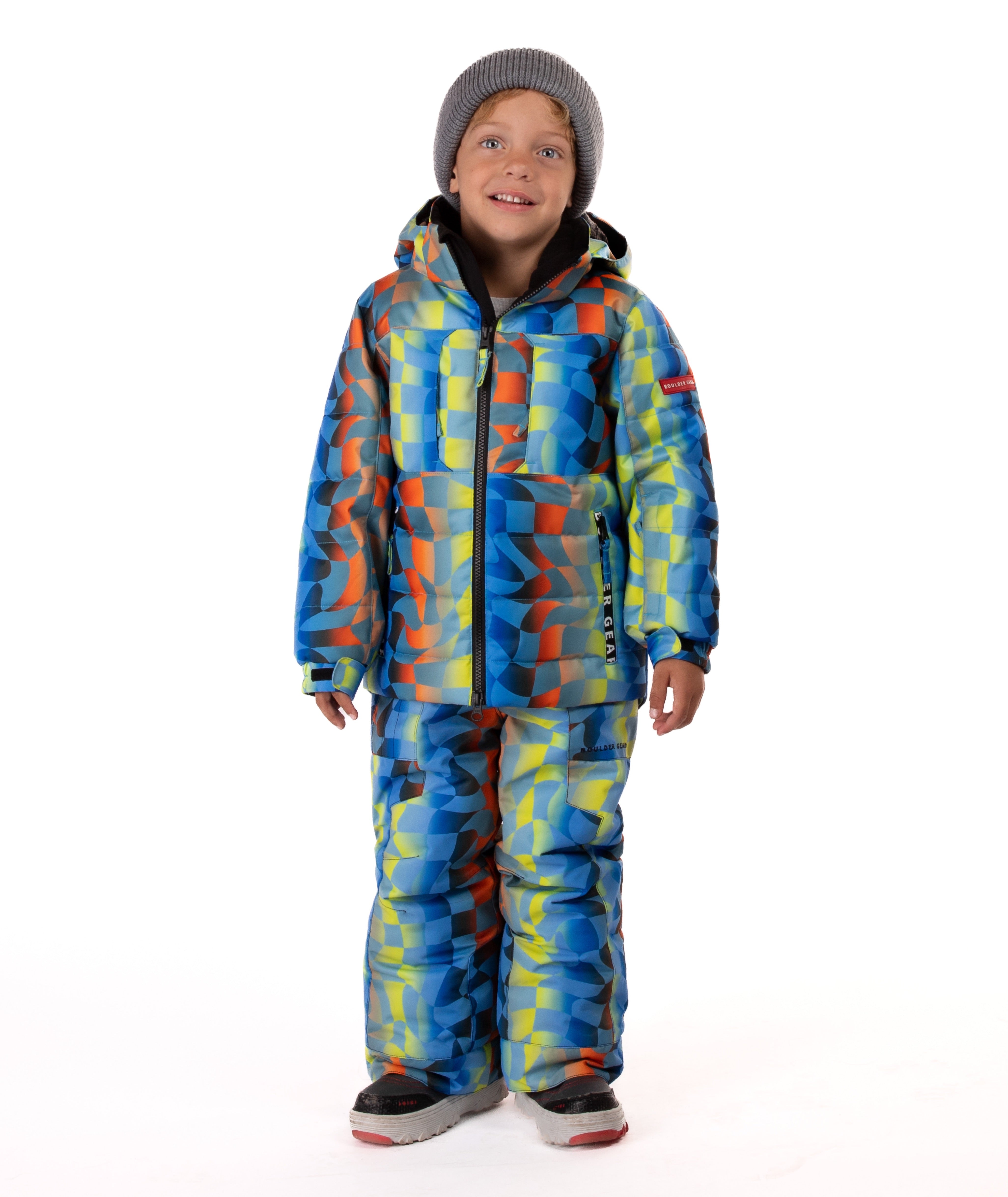 Child wearing a yellow, blue, and orange multi color geometric print quilted winter jacket with chest pockets and hand-warmer pockets on a white background