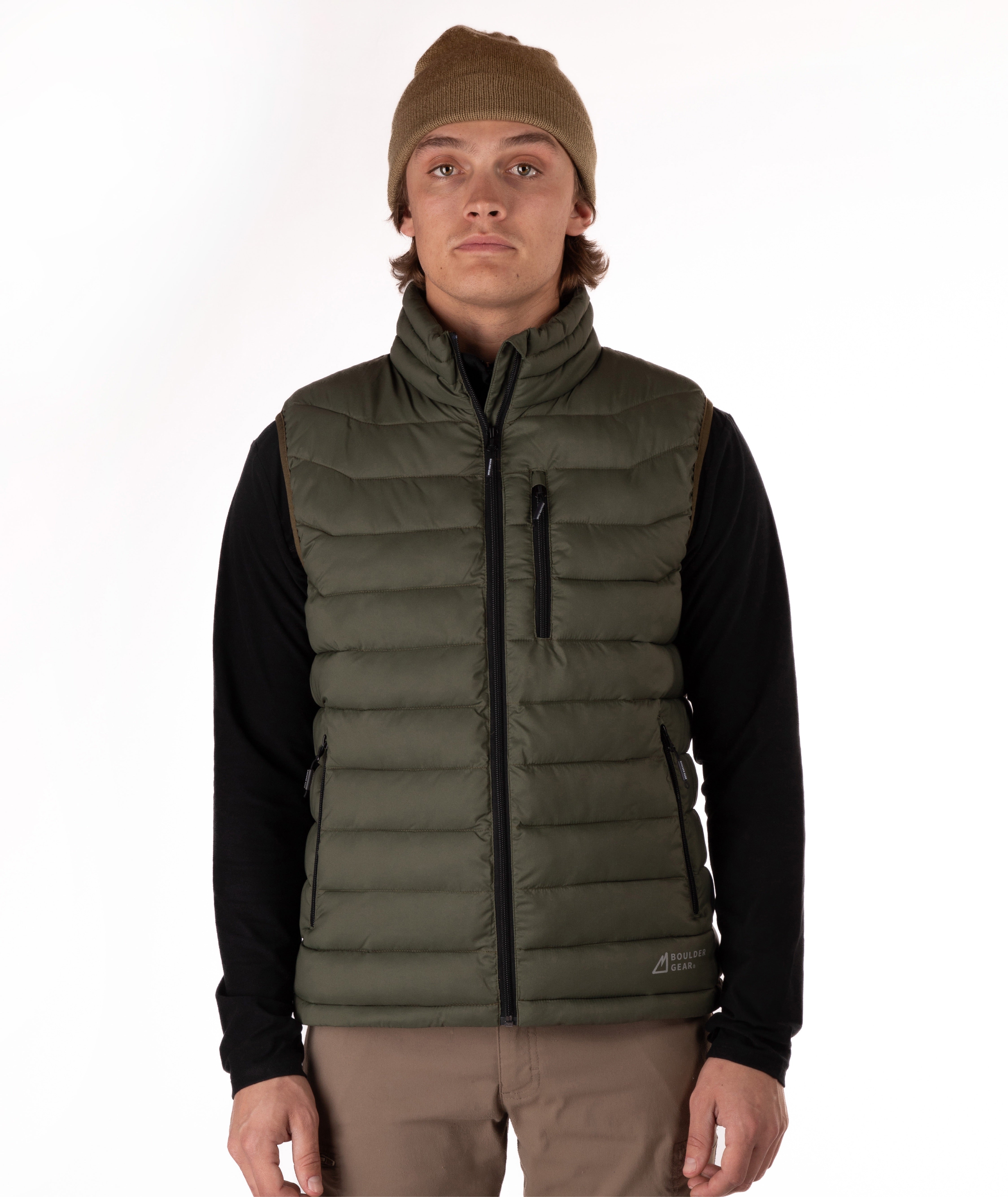 A man wearing an olive green puffer vest over a black long-sleeve shirt, with a brown beanie and tan pants, standing against a plain white background.
