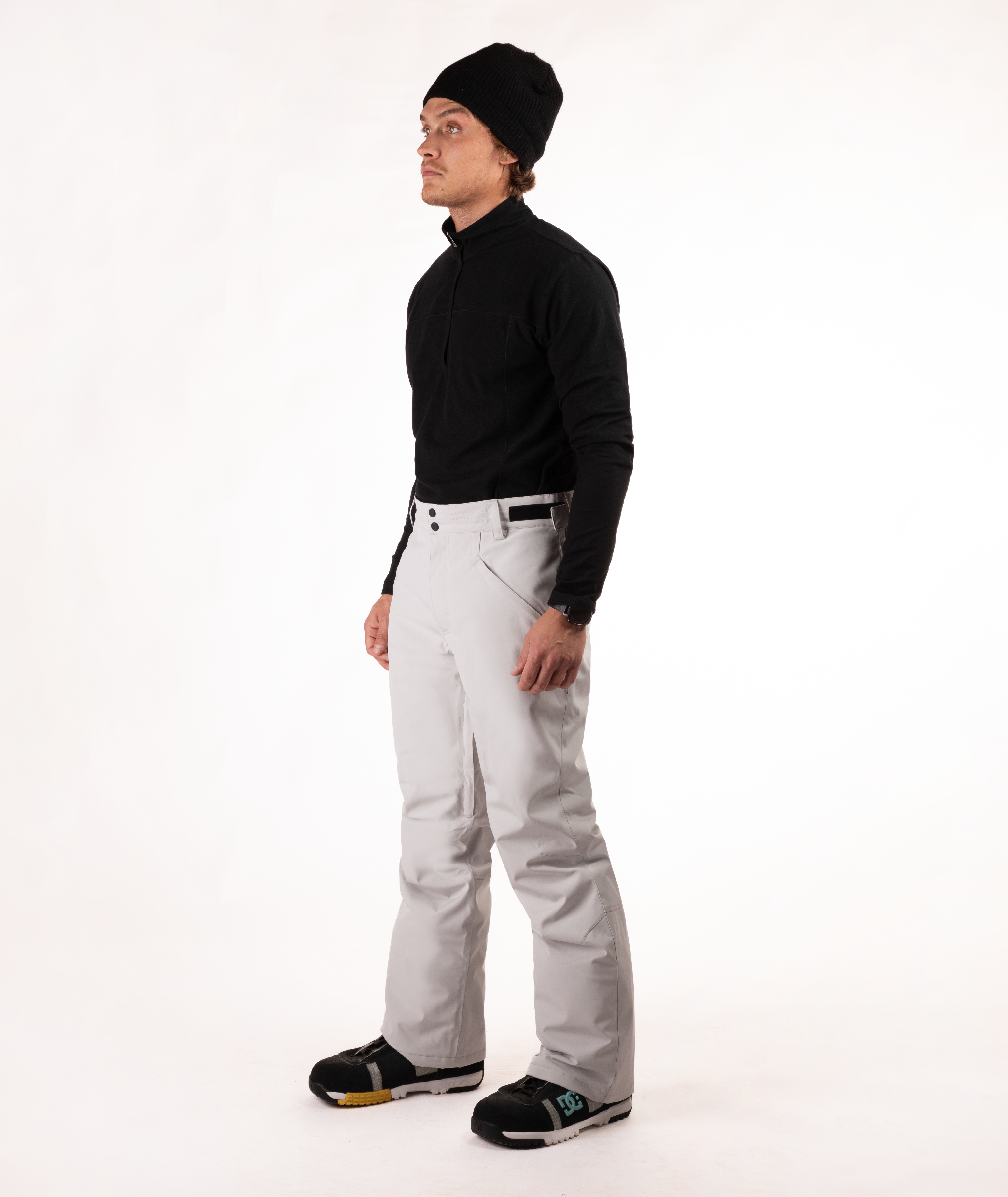 Person wearing a black top and light gray snow pants on a white background